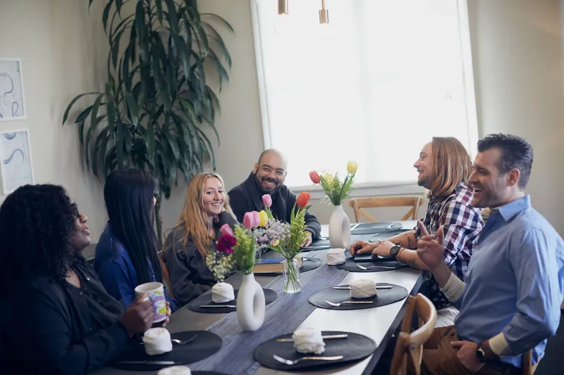 Clients and staff talking together around a table at Luna