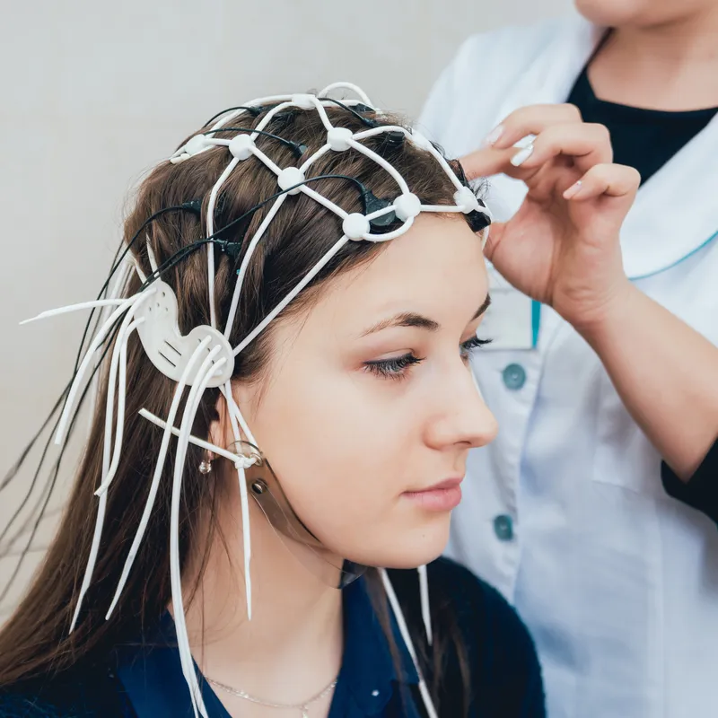 A clinician fitting an EEG electrode cap on a client for a QEEG brain map